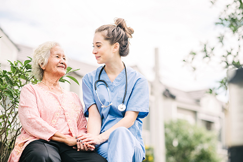Nursing sitting outside with elderly female resident
