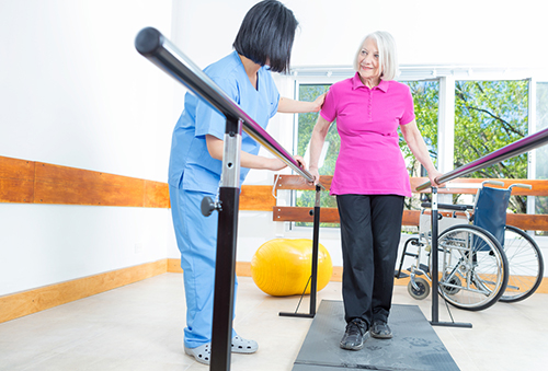 Rehab aide assisting elderly woman with rehab therapy